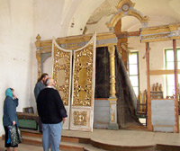 отец Александр показывает гостям разрушенный иконостас летнего храма